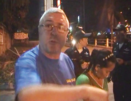 A battered and bruised Gary Bern stands with police officers at the scene of the attack.